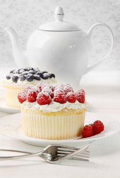 Cupcakes with raspberries and cream on table