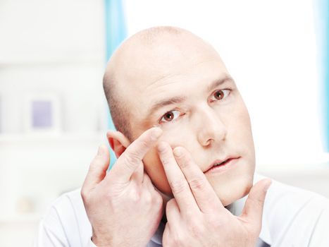 man putting contact lens in his eye