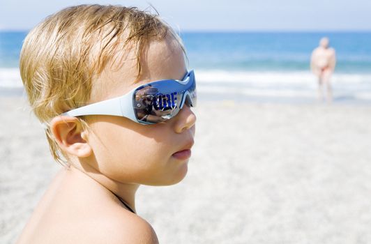 little boy with sunshades on a beach in summer time