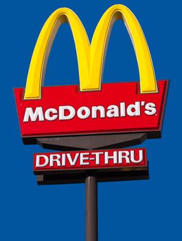 CAIRNS, AUSTRALIA - DECEMBER 2: McDonald's  logo and drive-thru sign against a blue sky background on Dec. 3, 2010 in Cairns, Australia.