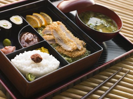 Tonkatsu Box and Miso Soup with Pickles and Sushi on a tray