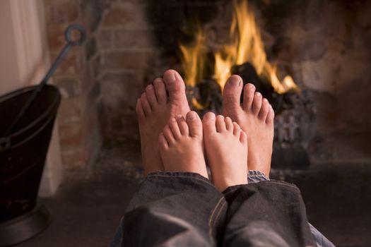 Father and son's Feet warming at a fireplace