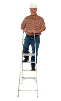 Worker wearing hard hat climbing ladder