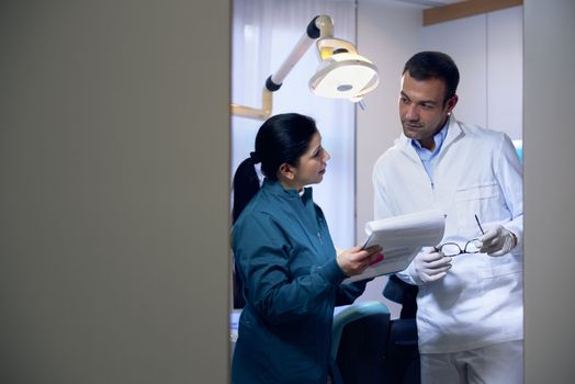Dentist and assistant checking documents in dental studio