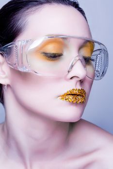 Young caucasian woman with gold fashion makeup wearing clear glasses and gold diamonties on her lips
