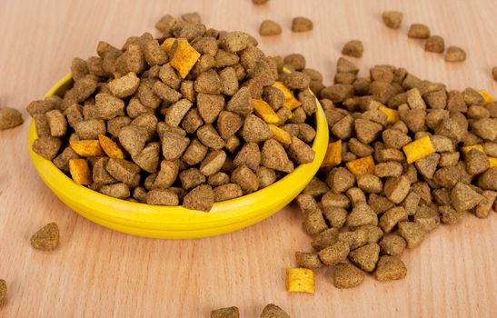 Dog food in bowl on wood background