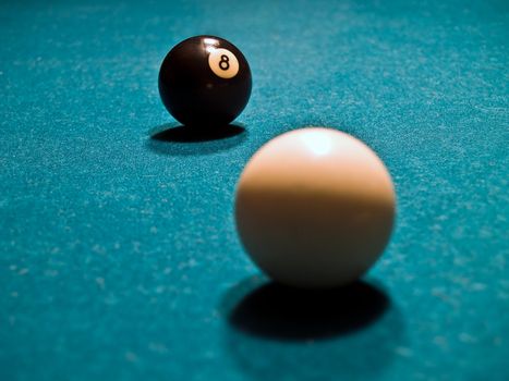 An Eight Ball and Cue Ball on a Green Billiards Table
