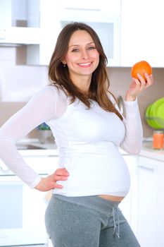Pregnant Young Woman Eating Fruits at home kitchen