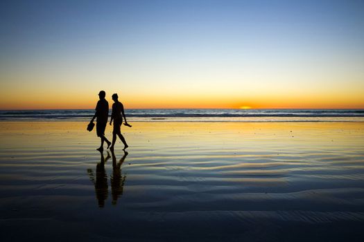 Young Couple Walking on Romantic Beach at Sunset