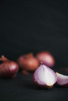 Full and half cut spanish onions on dark background.
