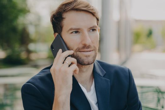 Horizontal shot of male entrepreneur or manager consults client by telephone call