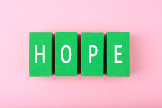 Hope single word written on green blocks against bright pink background