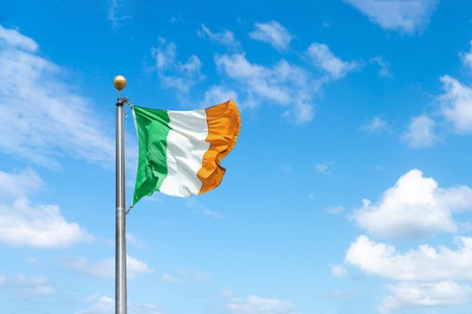 Irish tricolour flying in full sunshine against blue sky