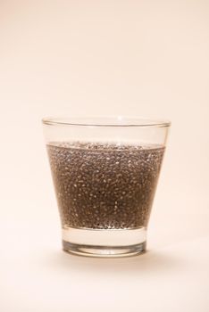 Glass of water with cup of healthy chia seeds and spoon. Text space.