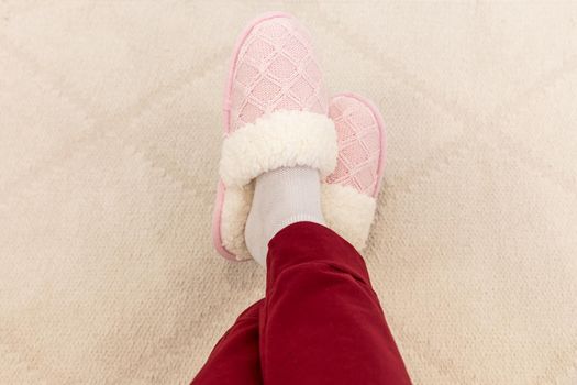 Crossed legs wearing pink knitted slippers