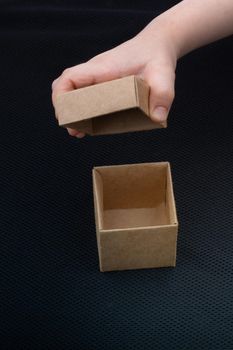 Hand opening cardboard box on a black background 