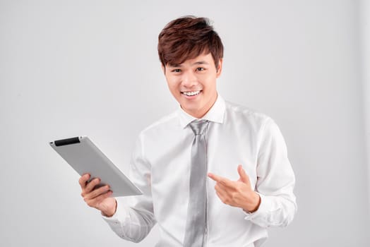  handsome surprised young man pointing on tablet which he holds in one hand.