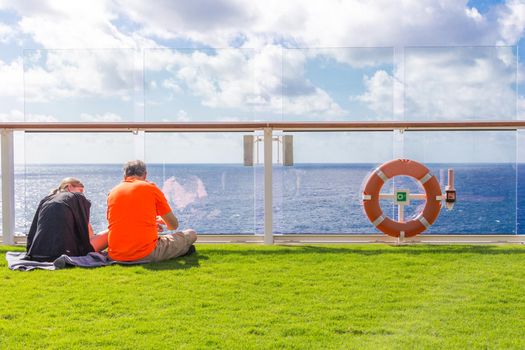 Couple sitting on real grass lawn on cruise ship