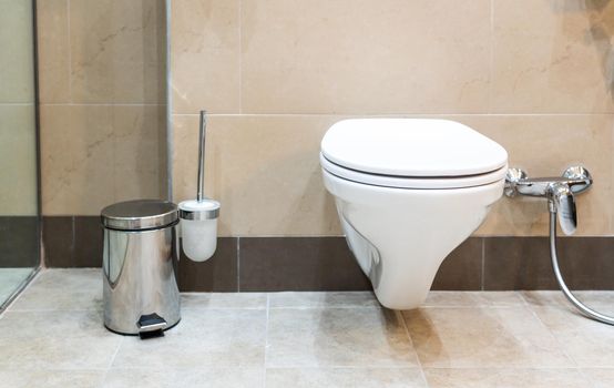 White toilet bowl in a modern bathroom with shower
