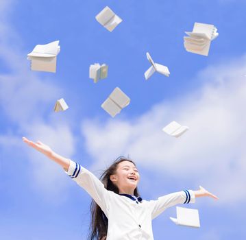 Happy friendly girl student throwing books fly in air