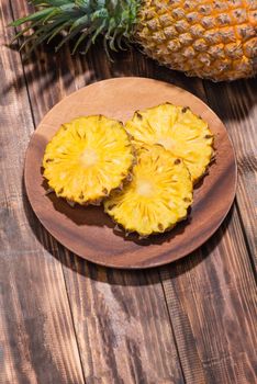 Fresh sliced pineapple on a wooden background.