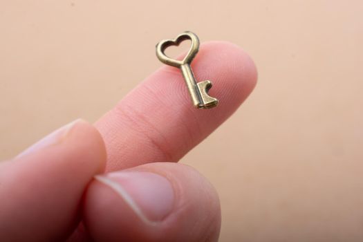 Tiny key with heart shape on the finger tip