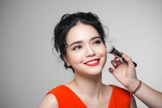 Portrait of attractive asian young adult woman applying blusher