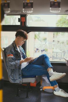 Handsome young man traveling by bus and using a digital tablet