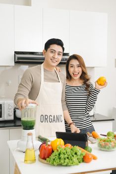 Happy asian couple in love in kitchen making healthy juice 
