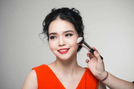Portrait of attractive asian young adult woman applying blusher