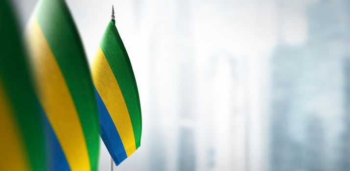Small flags of Gabon on a blurry background of the city