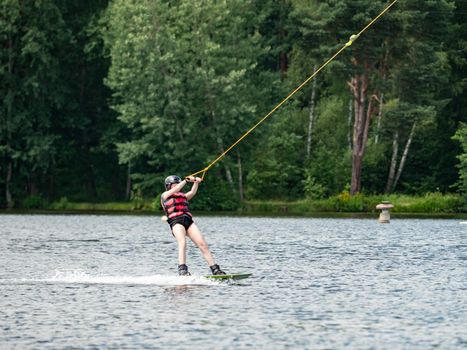 Wake boarding  boy on lake, the forest in blurry background.