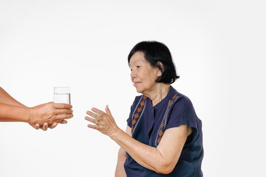 elderly woman gets a glass of water and her pills from caregiver