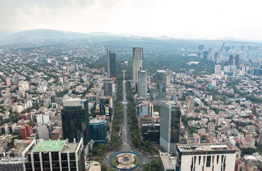 Aerial view of the Angel of Independence surrounded by greenery and commercial and financial building in Mexico City during day