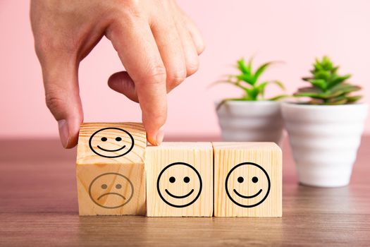 Customer service evaluation and satisfaction survey concepts. The client's hand turned the happy face smile on wooden blocks.