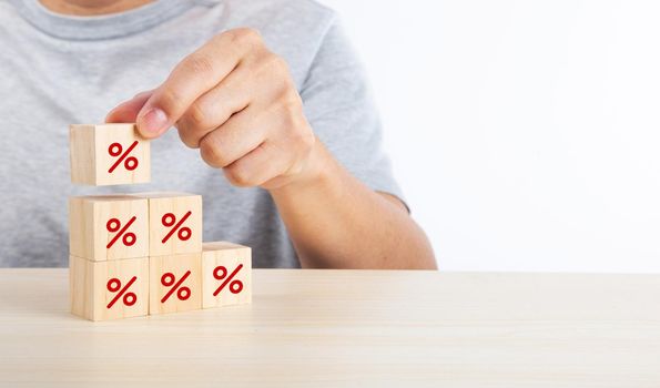 Hand putting wood cube block increasing on top with icon percentage symbol upward direction