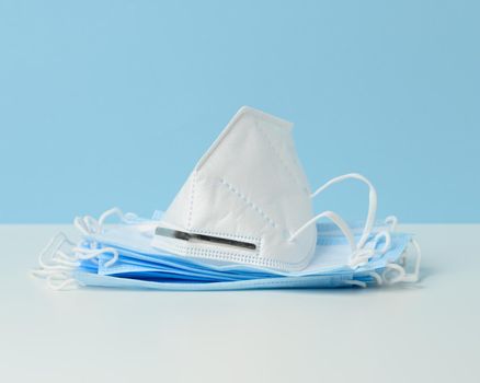 white disposable medical mask on a blue background, personal protective equipment for the respiratory tract from viral infections
