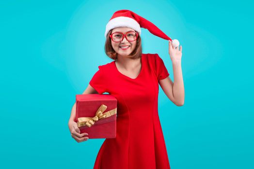 Mrs. Santa. Beautiful young asian woman in santa's hat holding a gift isolated on blue.