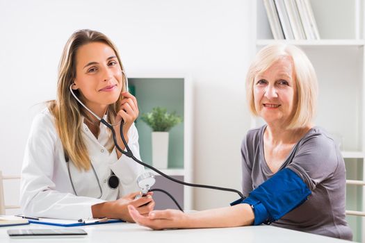 Female doctor is measuring blood pressure to her senior patient