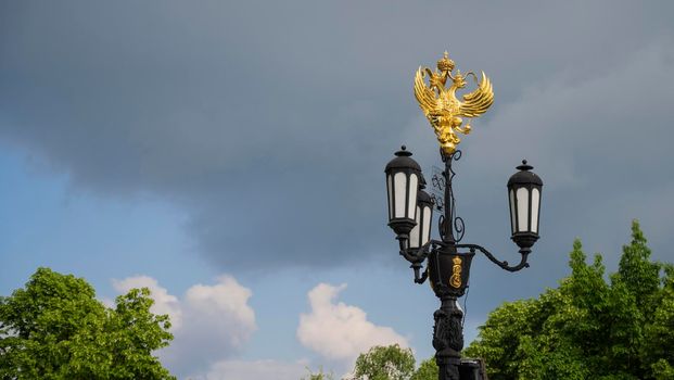 A street lamp with the coat of arms of Russia in Krasnodar, Russia. Cloudy Day May 23, 2021