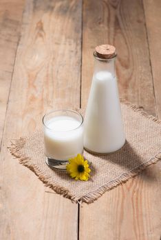 A bottle of soy milk or soya milk and soy beans on wooden table. 