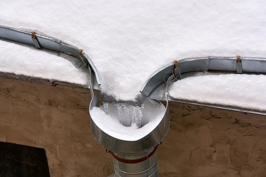 Snow and frozen water blocked the drain on the roof of the old house