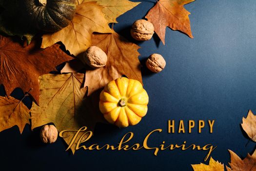 Happy Thanksgiving Day with maple leaves, nut and pumpkin on blue background