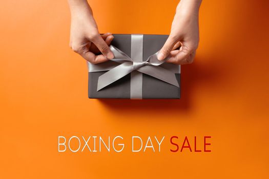 Boxing Day sale, young woman hand with a gift box offer to receiver