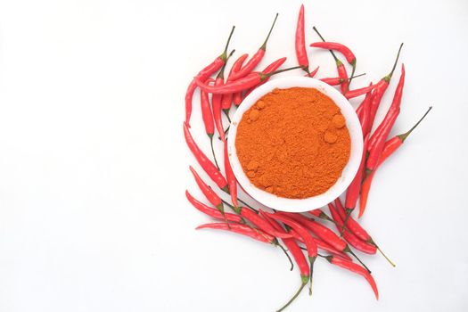 Chili powder and red peppers on white background.