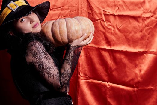 Halloween lady wearing witch cup and holding a big halloween pumpkin