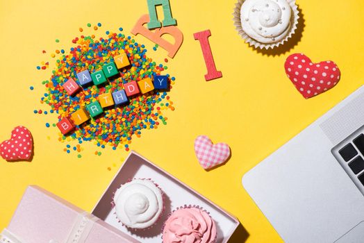 Delicious cupcake with laptop and Words Happy Birthday on yellow background