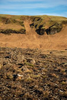 Icelandic topography with warm brown and orange tones and rocky texture with a blue sky