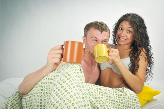 Young couple in bed with coffee