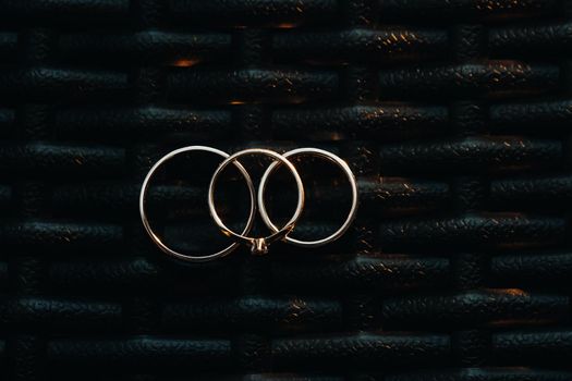 Two wedding rings and one engagement ring on a checkered grid. three gold rings of a couple in love on a gray background.Concept of love.Wedding ring
